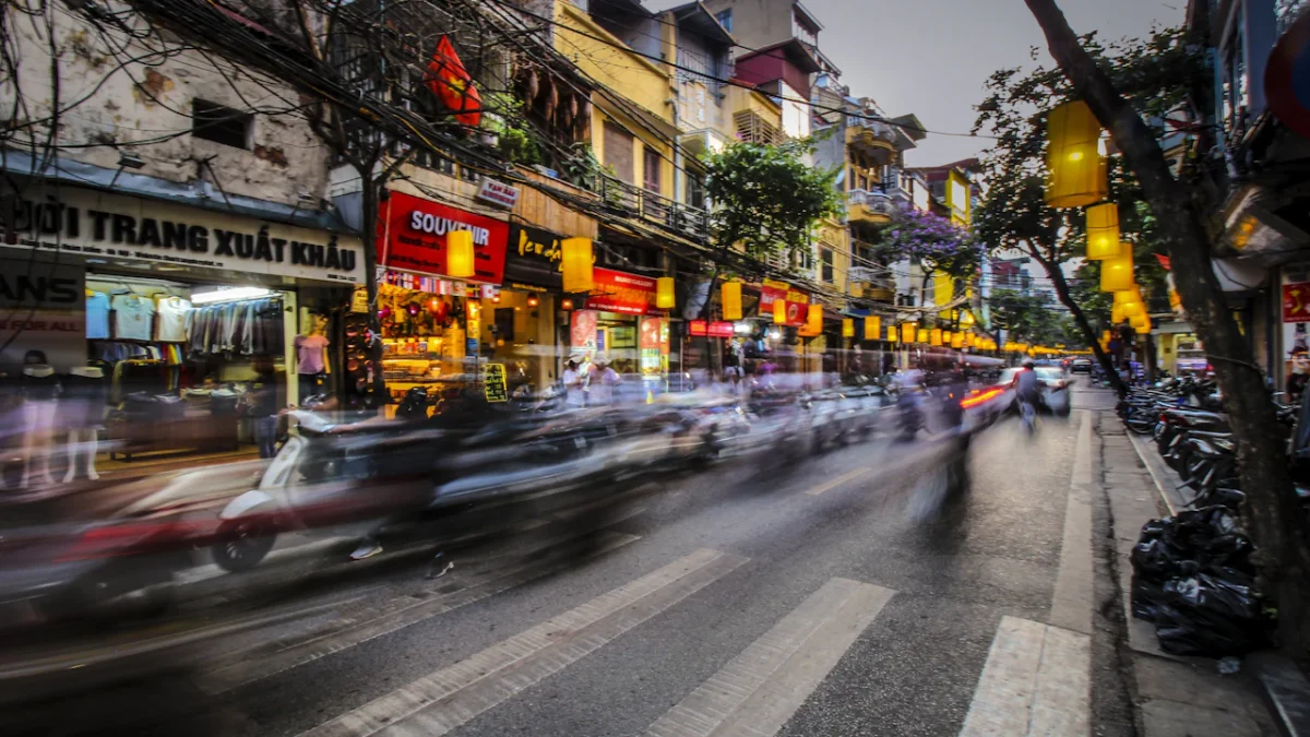 Evening scooter traffic blurring past shopfronts on a busy street in Hanoi, Vietnam