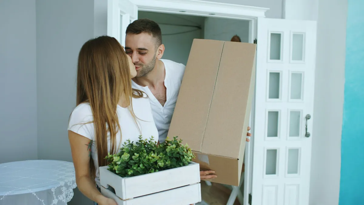 Couple moving boxes into a new home
